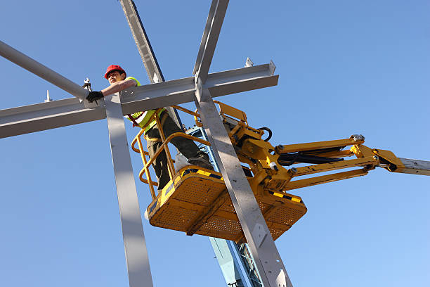 Steel worker assembling the framework of a new building from a cherry-picker